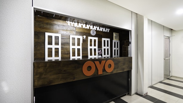 A reception desk with a wooden panel and a large 'OYO' sign. - OYO 89960 Manjung Inn Hotel (Sitiawan)