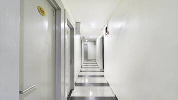 A corridor with a black and white tiled floor, white walls, and doors with numbers.