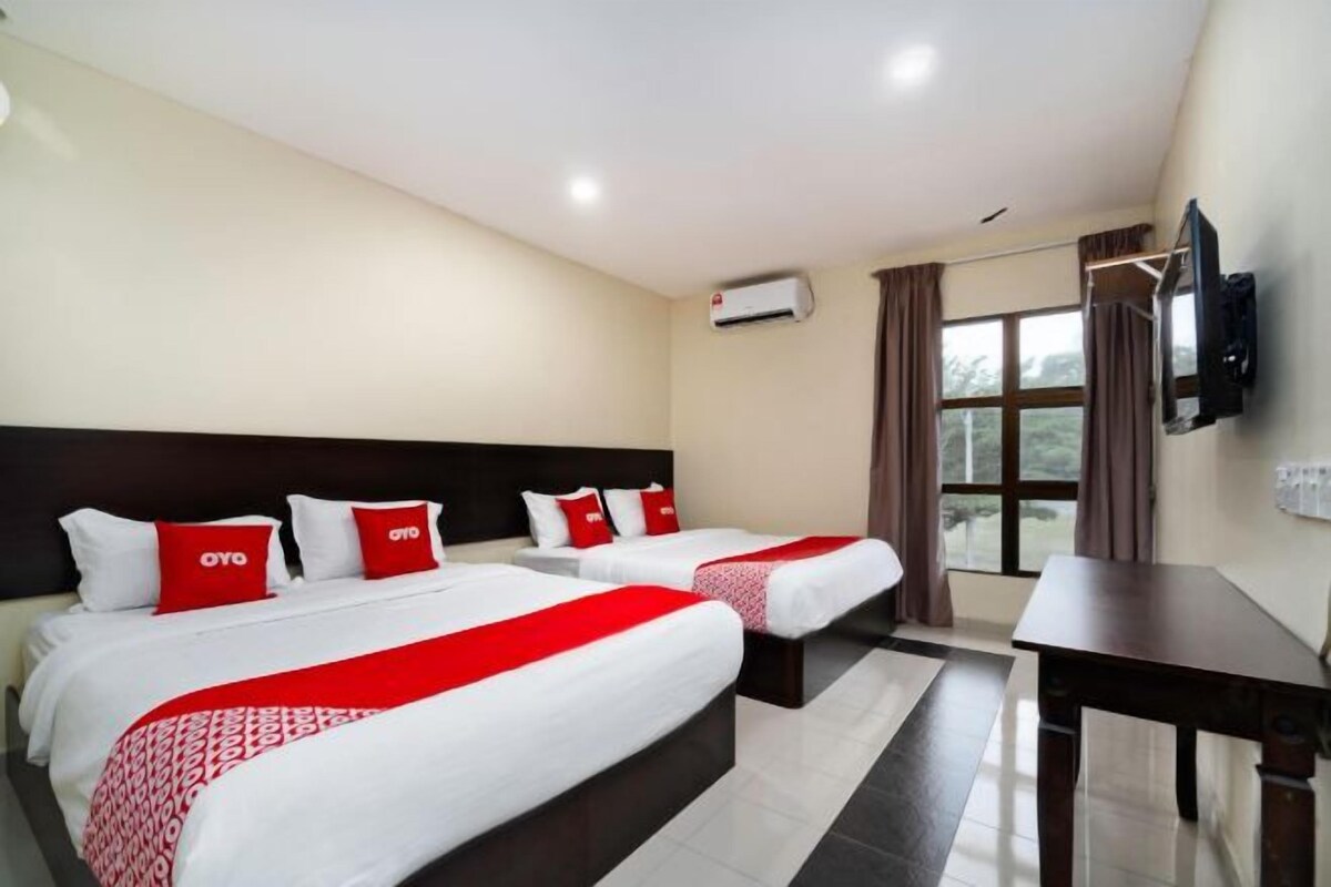 A hotel room with two beds, a TV mounted on the wall, and a window with curtains.