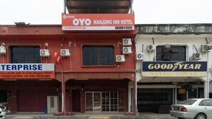 A building with a sign for OYO Manjung Inn Hotel and a Goodyear tire store. - OYO 89960 Manjung Inn Hotel (Sitiawan)