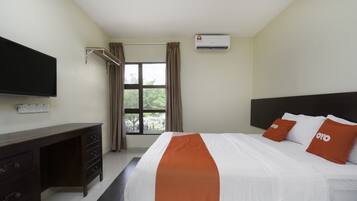 A hotel room with a bed, a desk, a TV, and an air conditioner.
