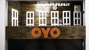 A reception desk with a wooden panel and the name "OYO" prominently displayed. - OYO 89960 Manjung Inn Hotel (Sitiawan)
