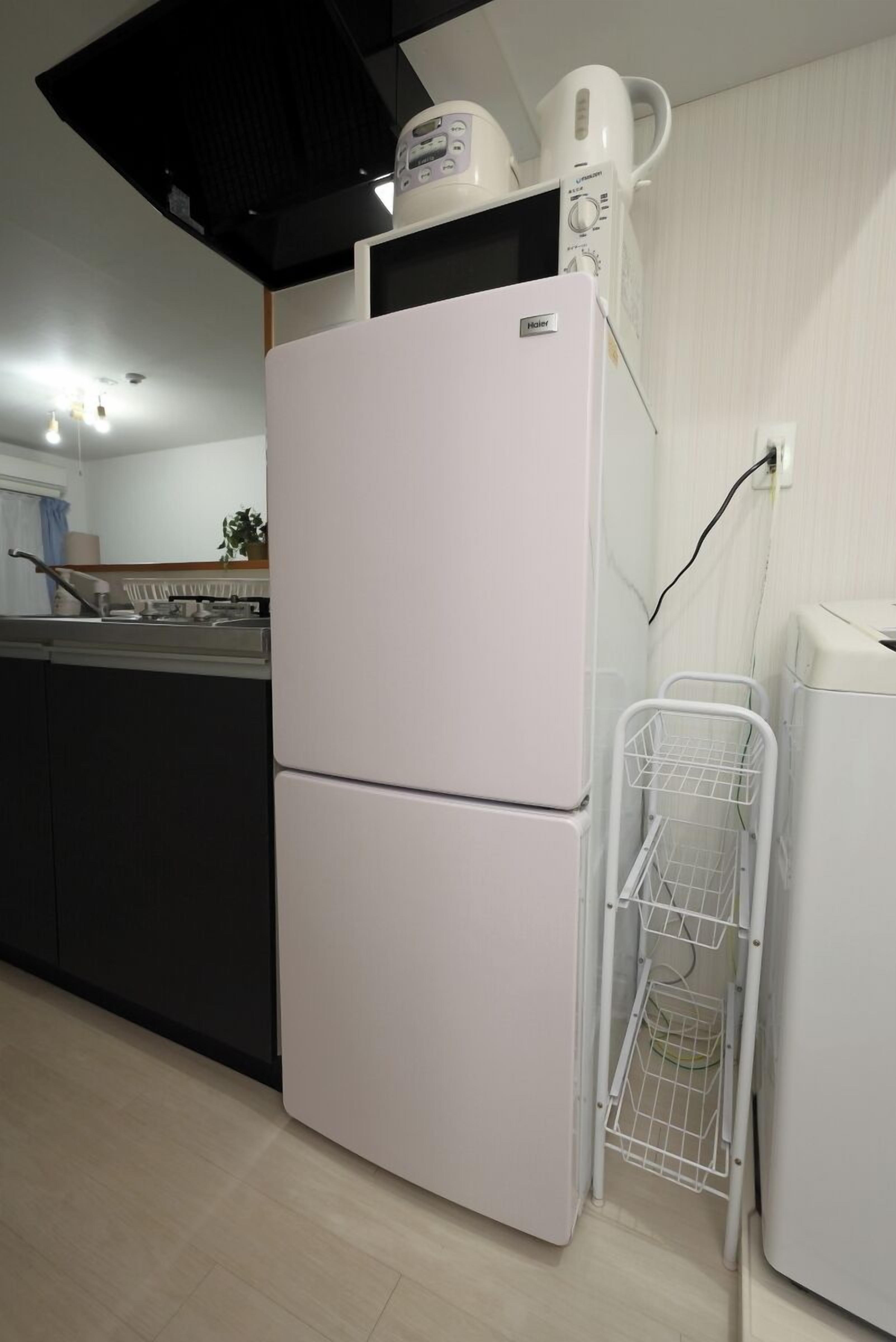 Eine Küche mit einem weißen Kühlschrank, einer Kaffeemaschine und einer Mikrowelle auf der Arbeitsplatte.