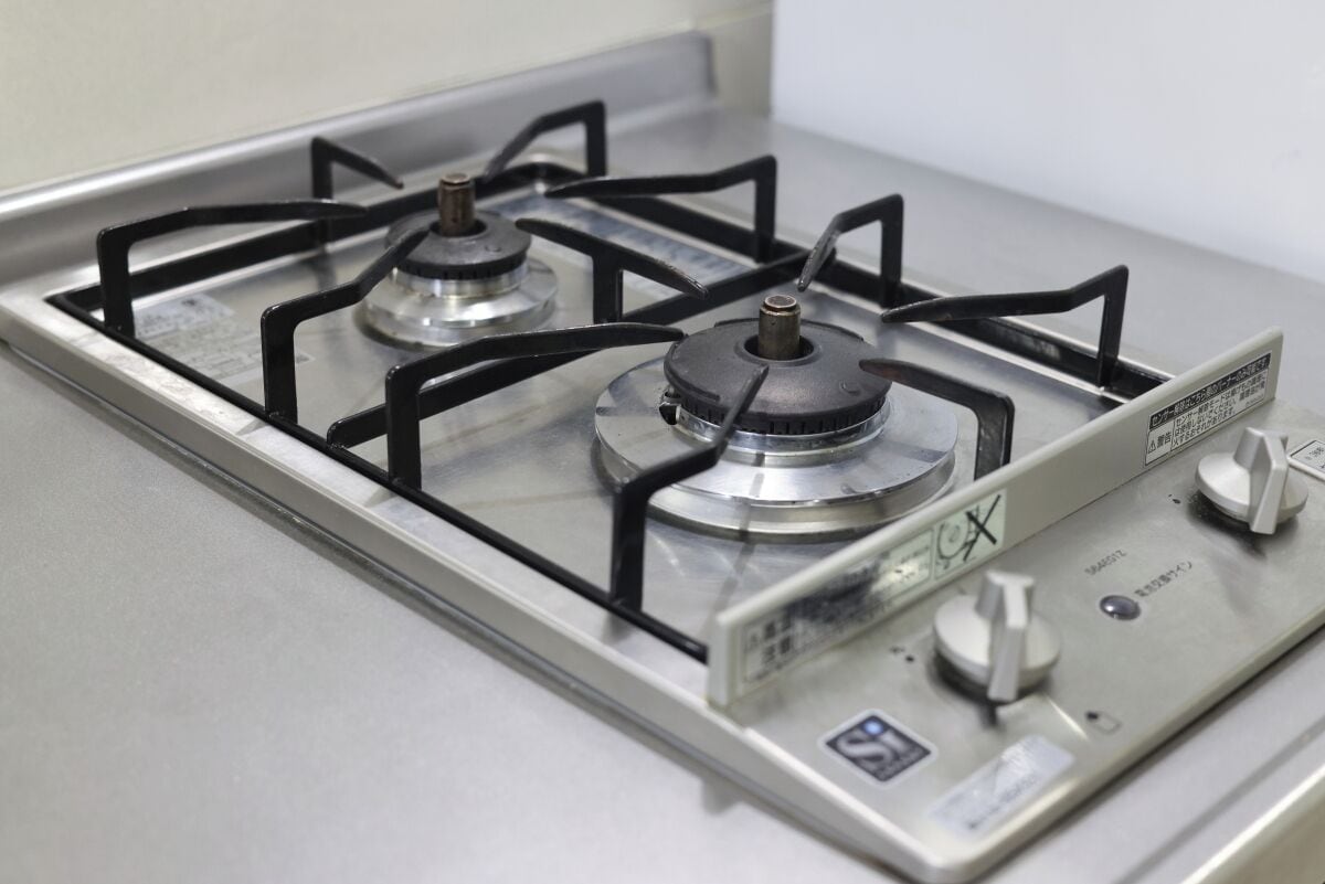 A gas stove with four burners and a control panel.