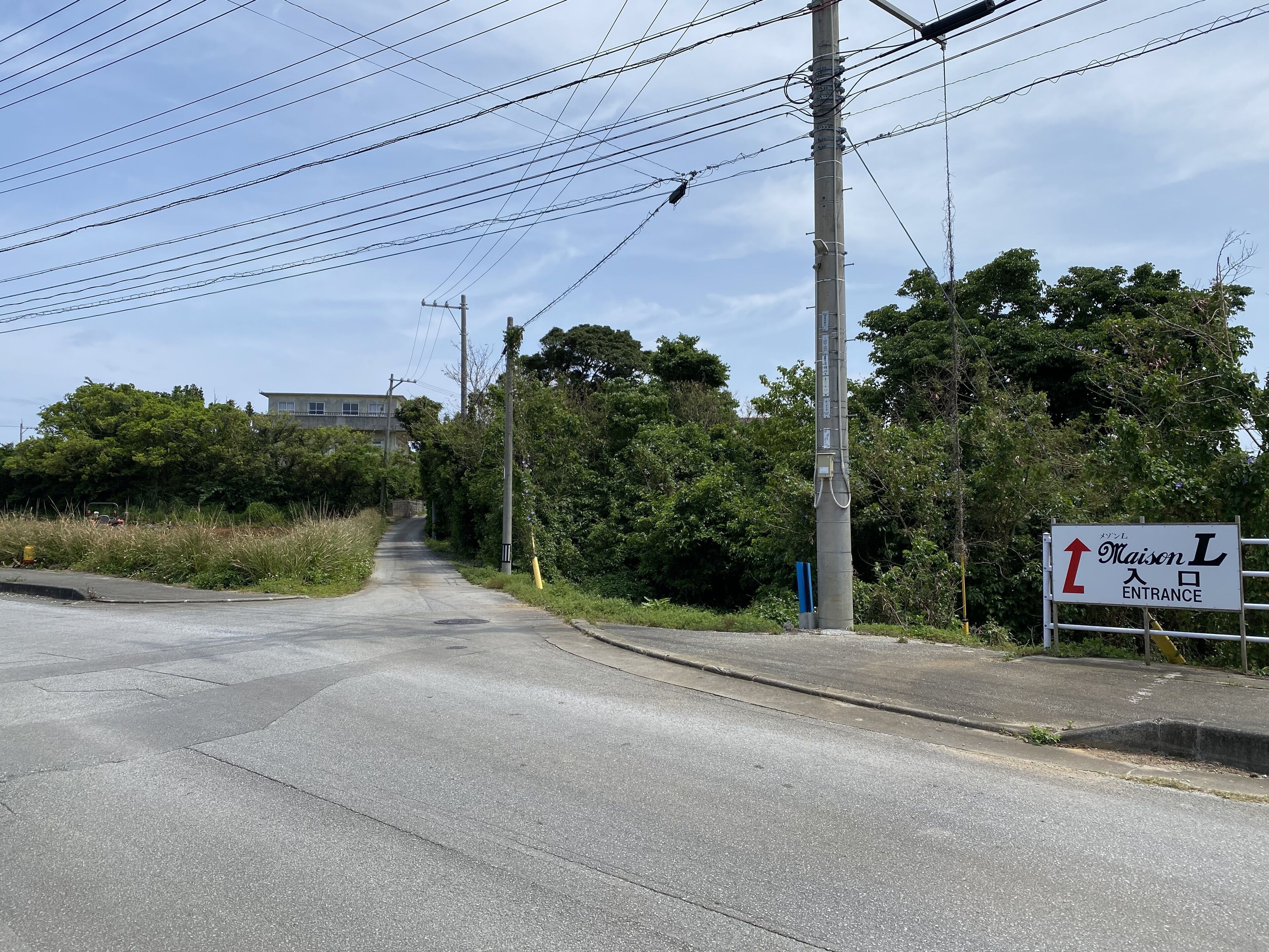 A road leading to a building with a sign indicating an entrance.