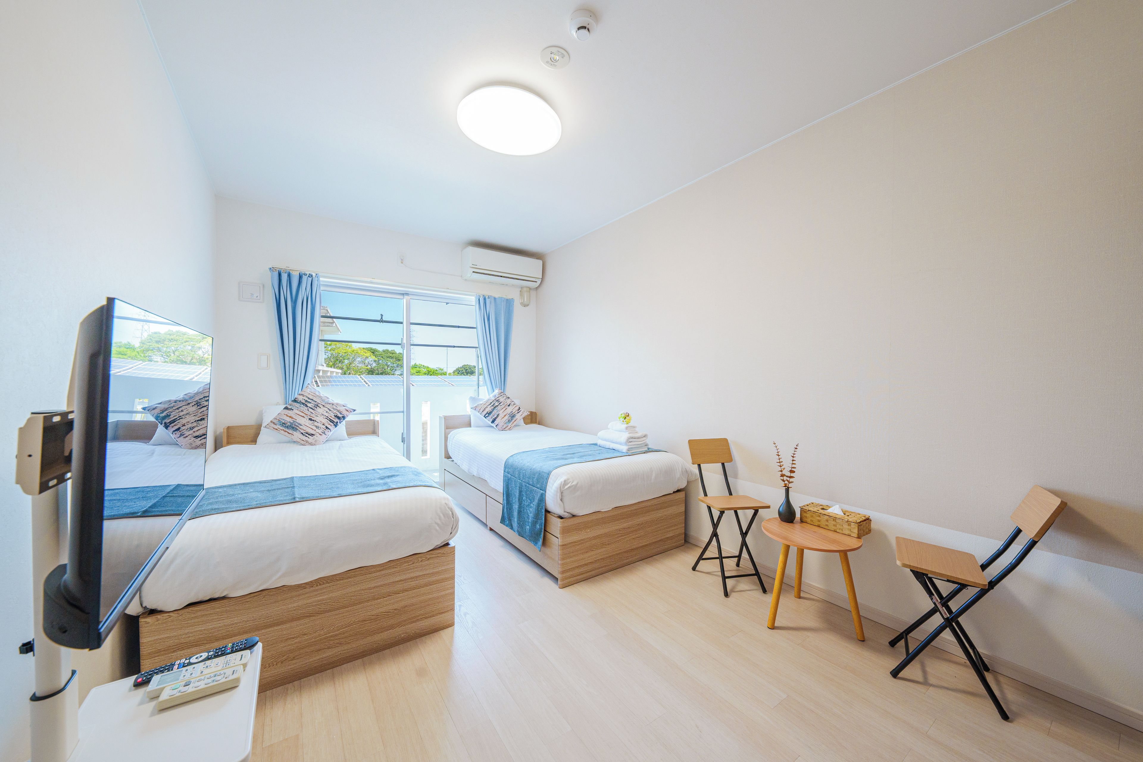 A hotel room with two beds, a TV, a small table, and a chair.