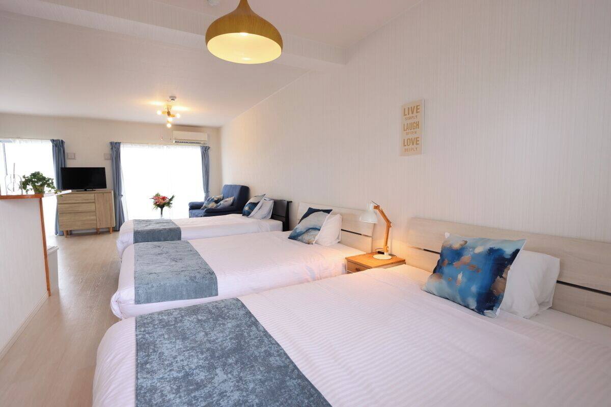 A hotel room with two beds, a TV, a desk, and a large window.