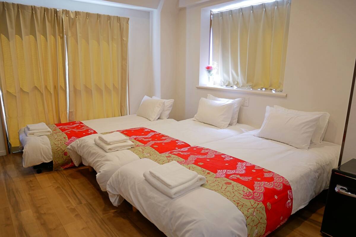 Une chambre d’hôtel avec deux lits, un plancher en bois et une fenêtre avec des rideaux.