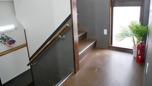 Eine moderne Treppe mit Holzgeländer, einem kleinen Topfpflanzen und einem Feuerlöscher in der Nähe des Fensters.