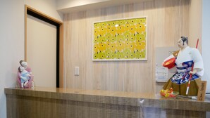 Ein Empfangsschalter mit Holzoptik, eine dekorative Statue und ein gerahmtes Blumenbild an der Wand.