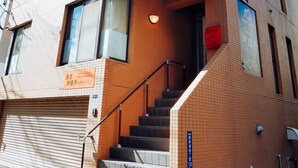 Ein mehrstöckiges Hotel mit modernem Design, das eine Treppe zum Eingang und Beschilderung in Englisch und einer anderen Sprache zeigt.
