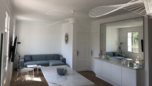 Un salon moderne comprenant un canapé, une table à manger et un coin cuisine avec un grand miroir et des placards.
