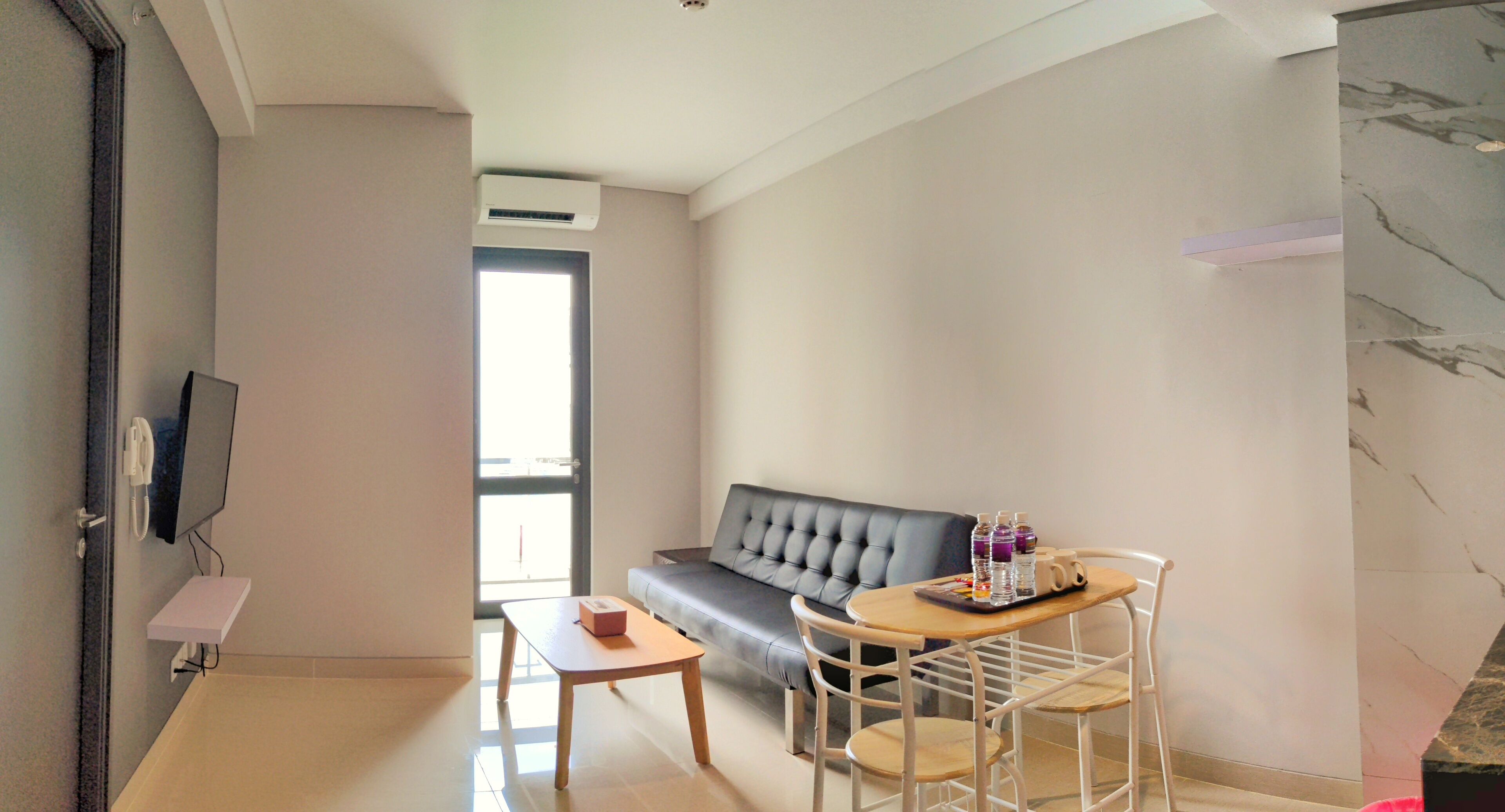 Una sala moderna con un sofá, una mesa de centro y una pequeña zona de comedor con sillas.