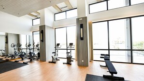 A gym with exercise equipment, large windows, and a wooden floor. -  Lovina at One Residence (Batam)