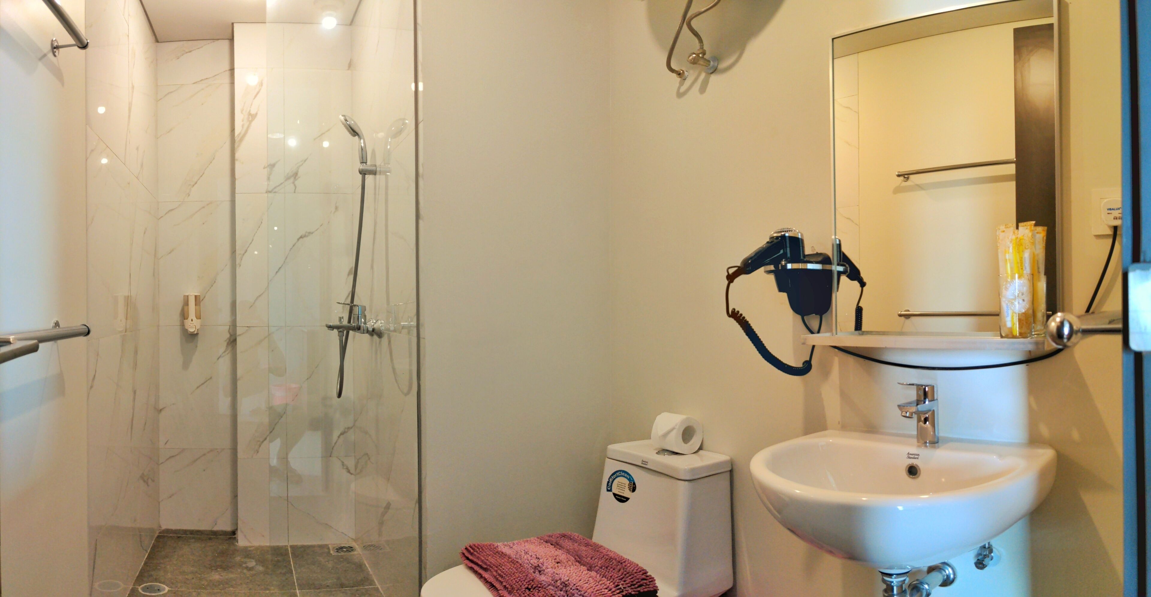 A modern bathroom with a glass-enclosed shower, a white sink, and a toilet.