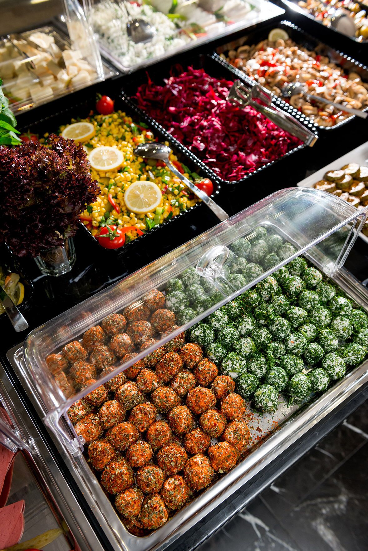 Un buffet proposant une variété de plats, notamment des salades, des boulettes de viande et d’autres mets.