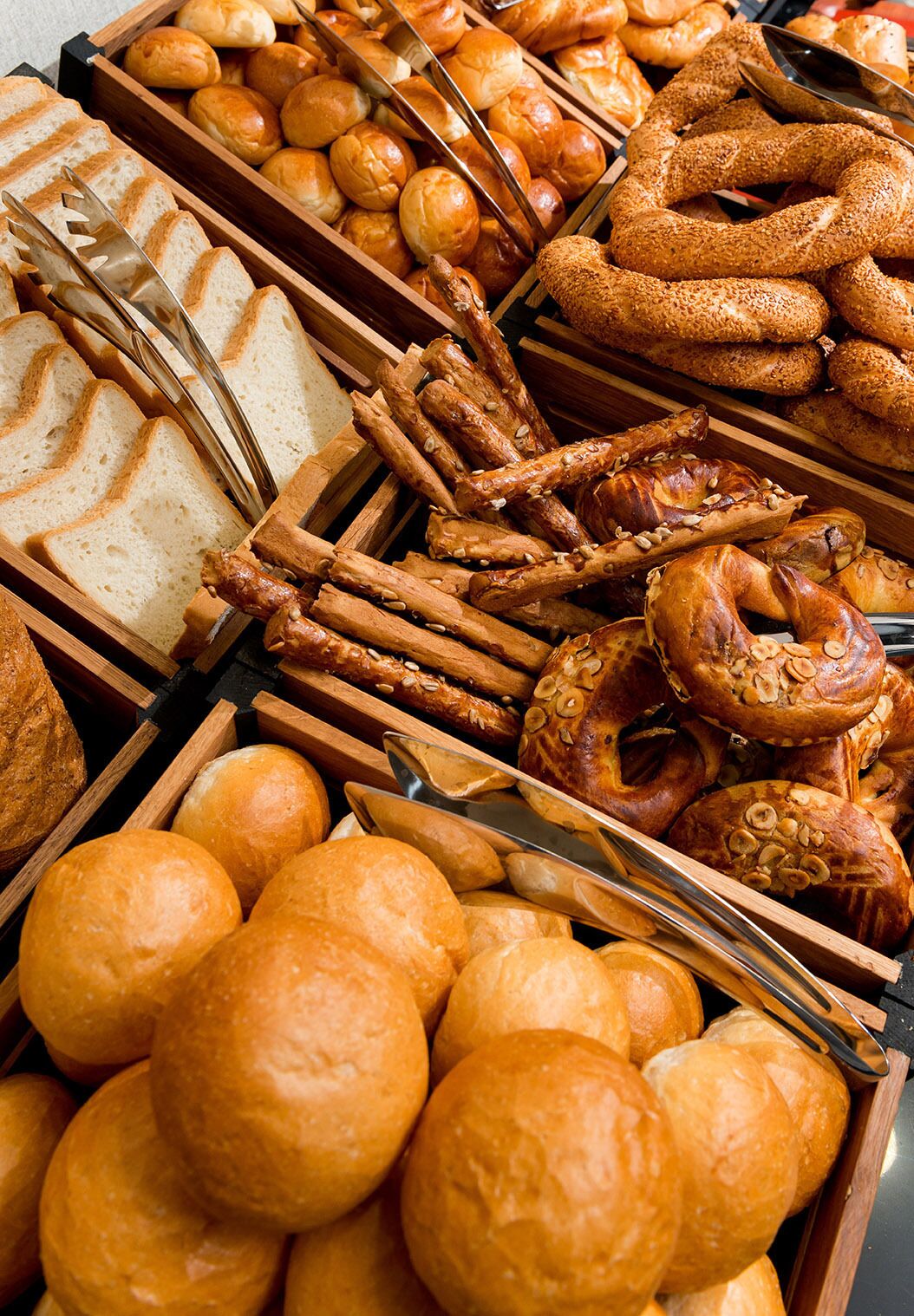 A variety of breads and pastries displayed in wooden trays.