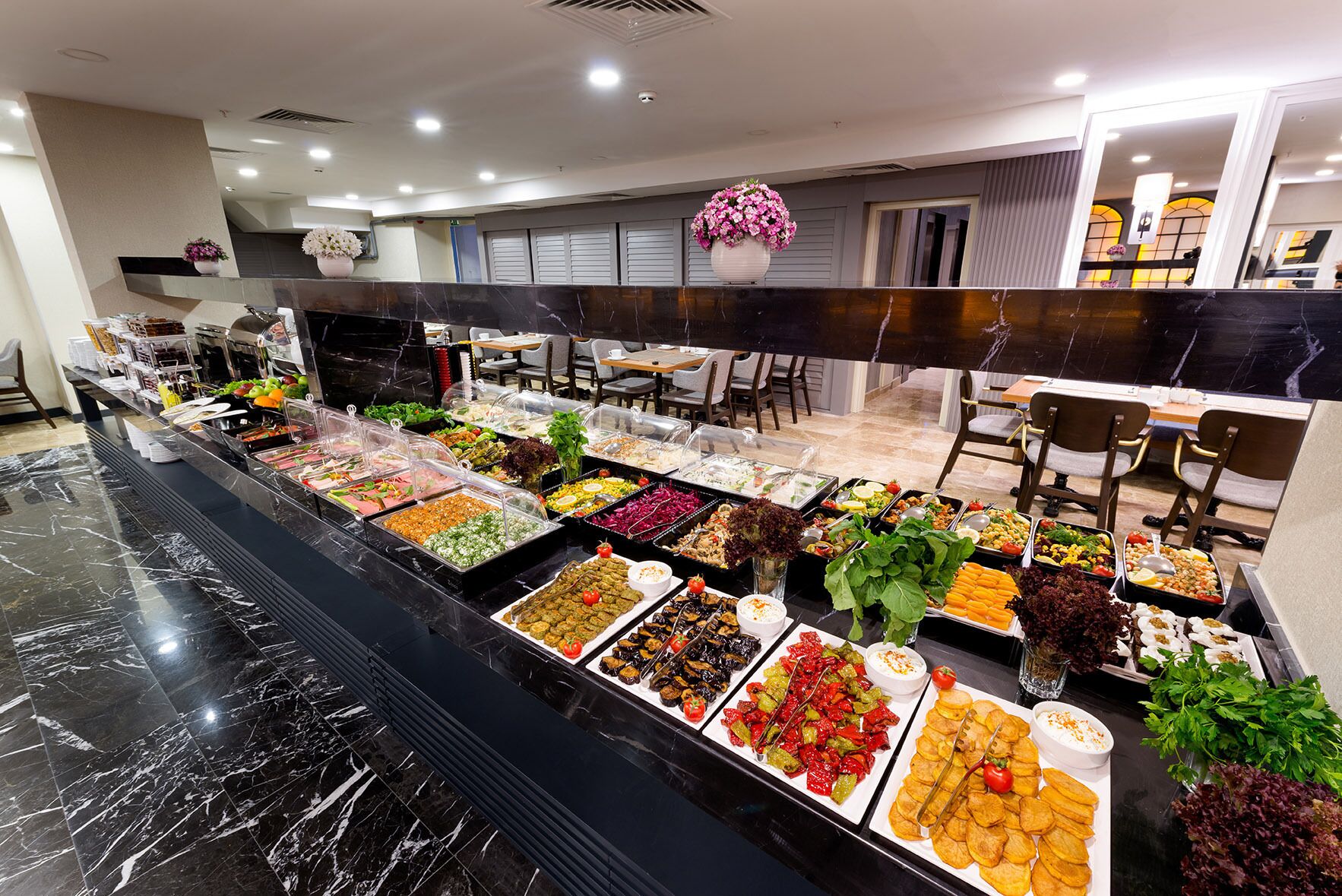 A buffet with various food options and a marble floor.