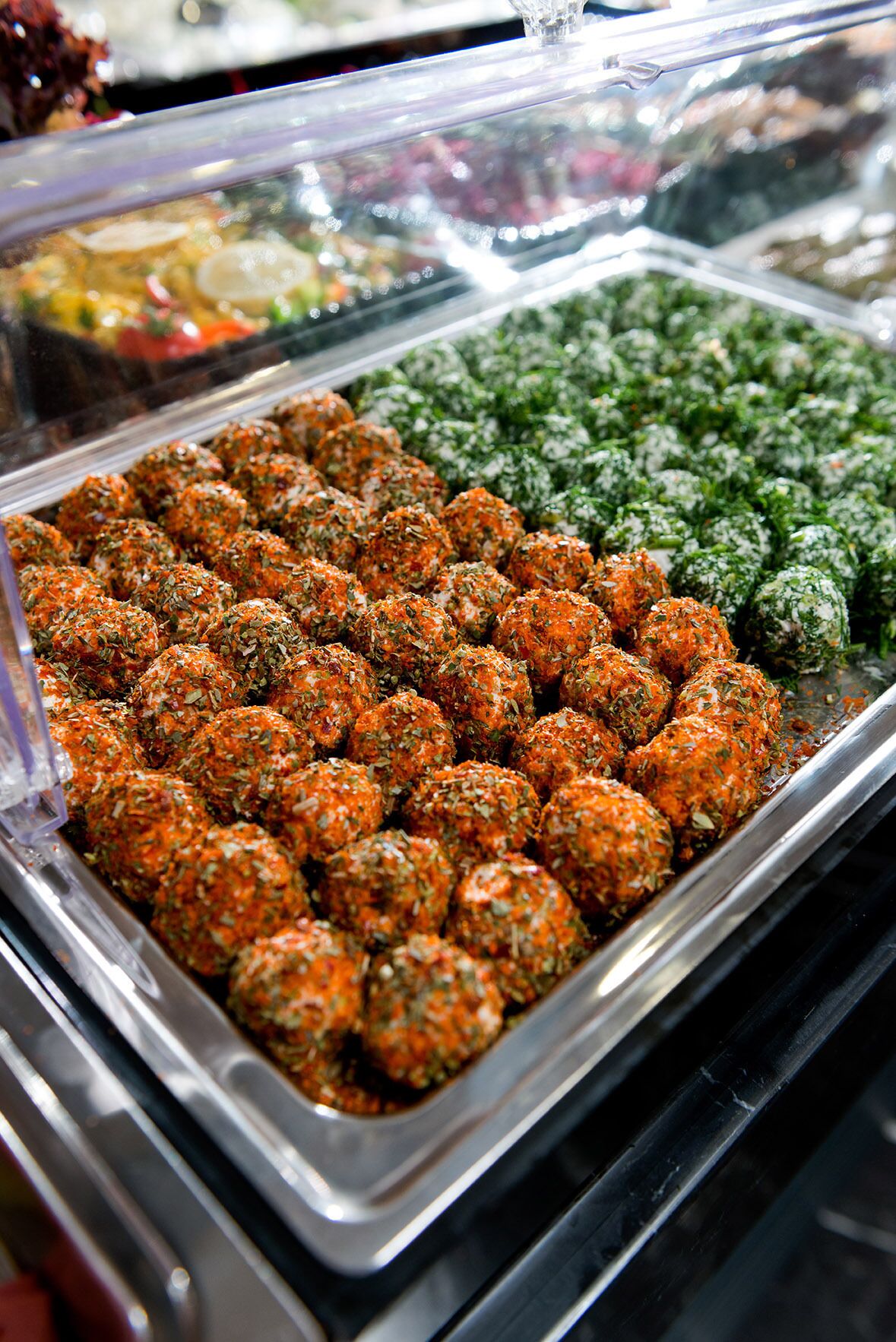 Ein Buffet mit verschiedenen Speisen, darunter Hackbällchen und ein grüner Salat.