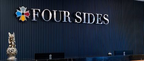 A reception desk with a sign reading "FOUR SIDES" and a logo above it.