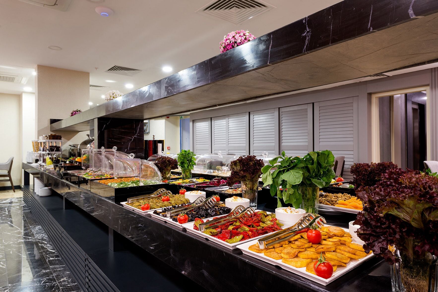 A buffet with various food items and fresh vegetables.