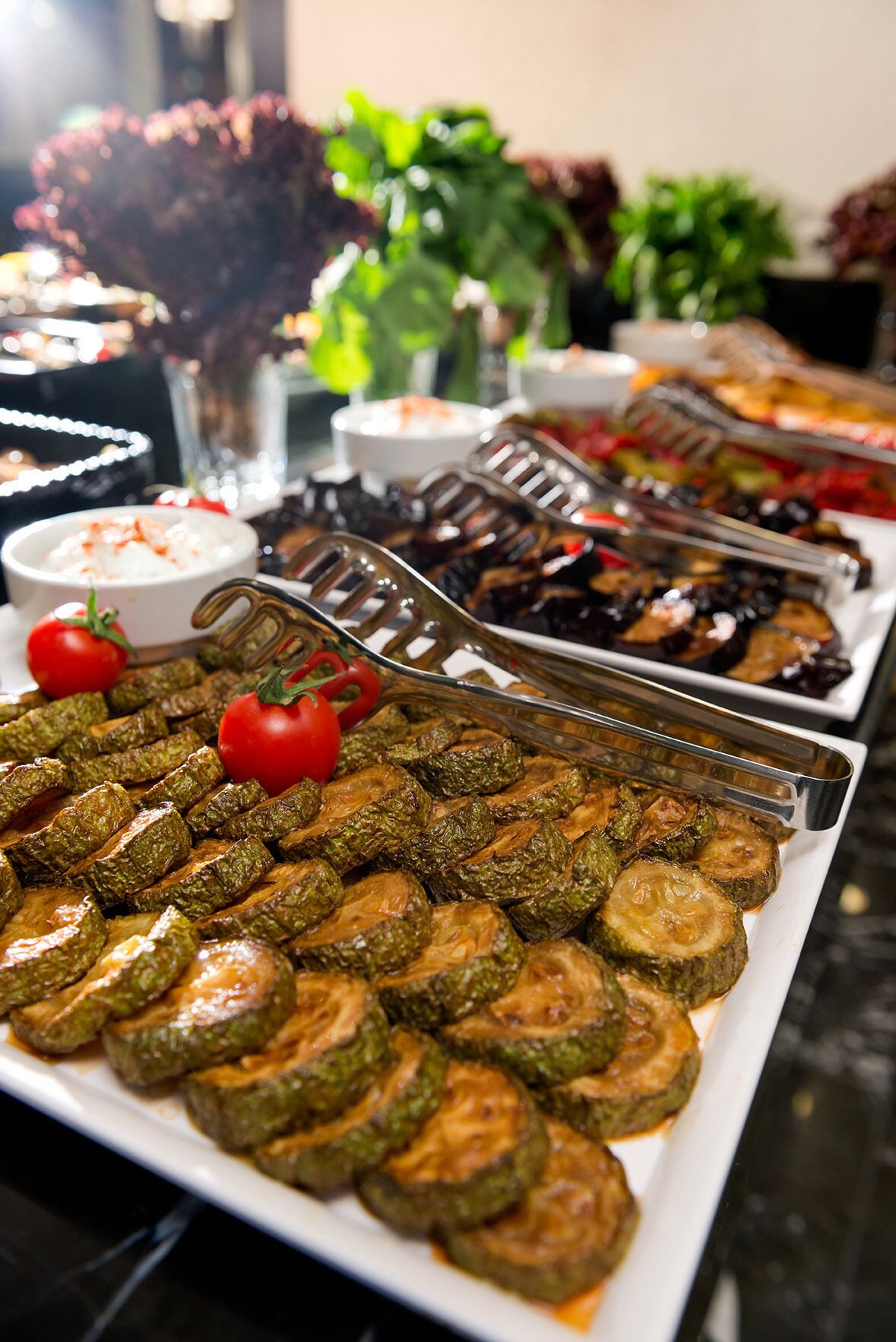 A buffet with various dishes including roasted vegetables and a bowl of dip.