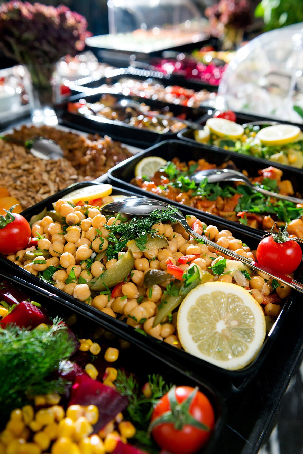 A buffet with various dishes including chickpeas, vegetables, and garnishes.