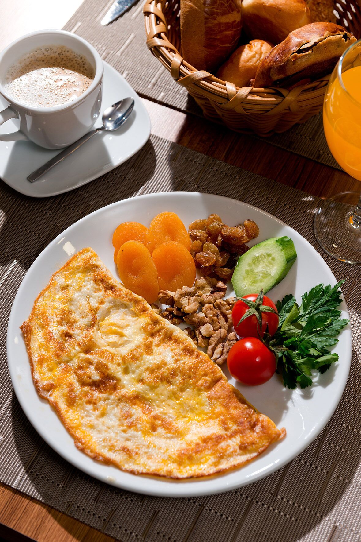 A breakfast plate with an omelette, fruits, nuts, and vegetables.