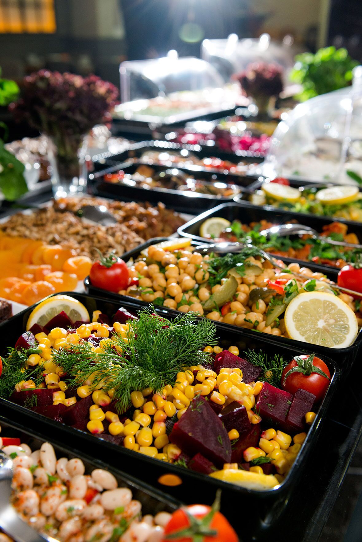 A buffet with various dishes including corn, beans, and vegetables.