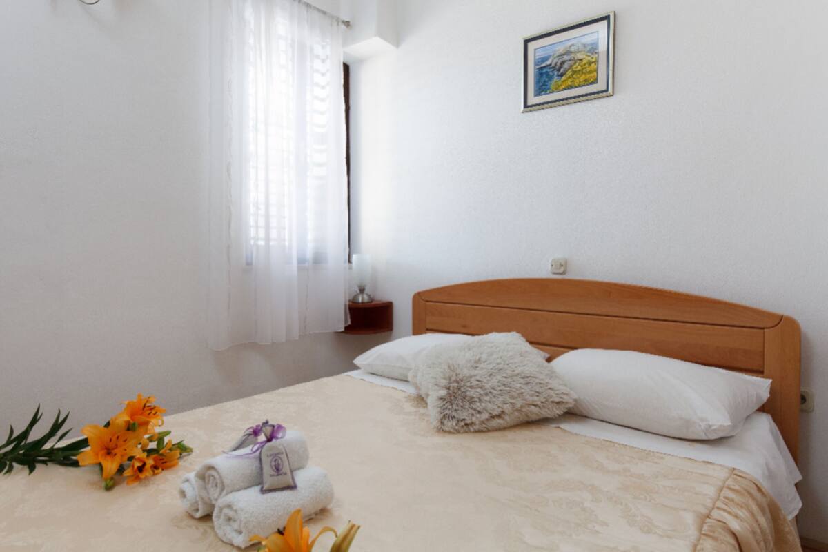 Un lit bien fait, avec du linge de lit blanc et un oreiller moelleux, une table de chevet avec une lampe et un tableau encadré au mur.