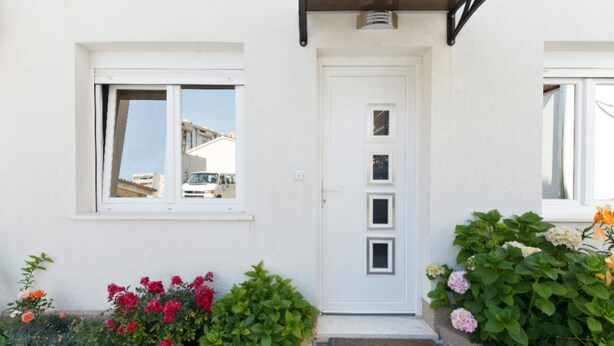 A white building with a white door, a window, and a small porch area with plants. - Tihi Val Apartments (Split)