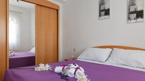 A hotel room with a bed, a wooden wardrobe, a nightstand, and a mirror. - Tihi Val Apartments (Split)