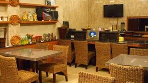 Un restaurante con mobiliario de mimbre, un televisor y estantes con salsas y aderezos.