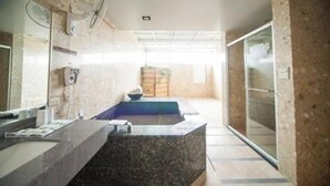 Un baño moderno con encimera de granito, un espejo grande y un lavamanos empotrado.