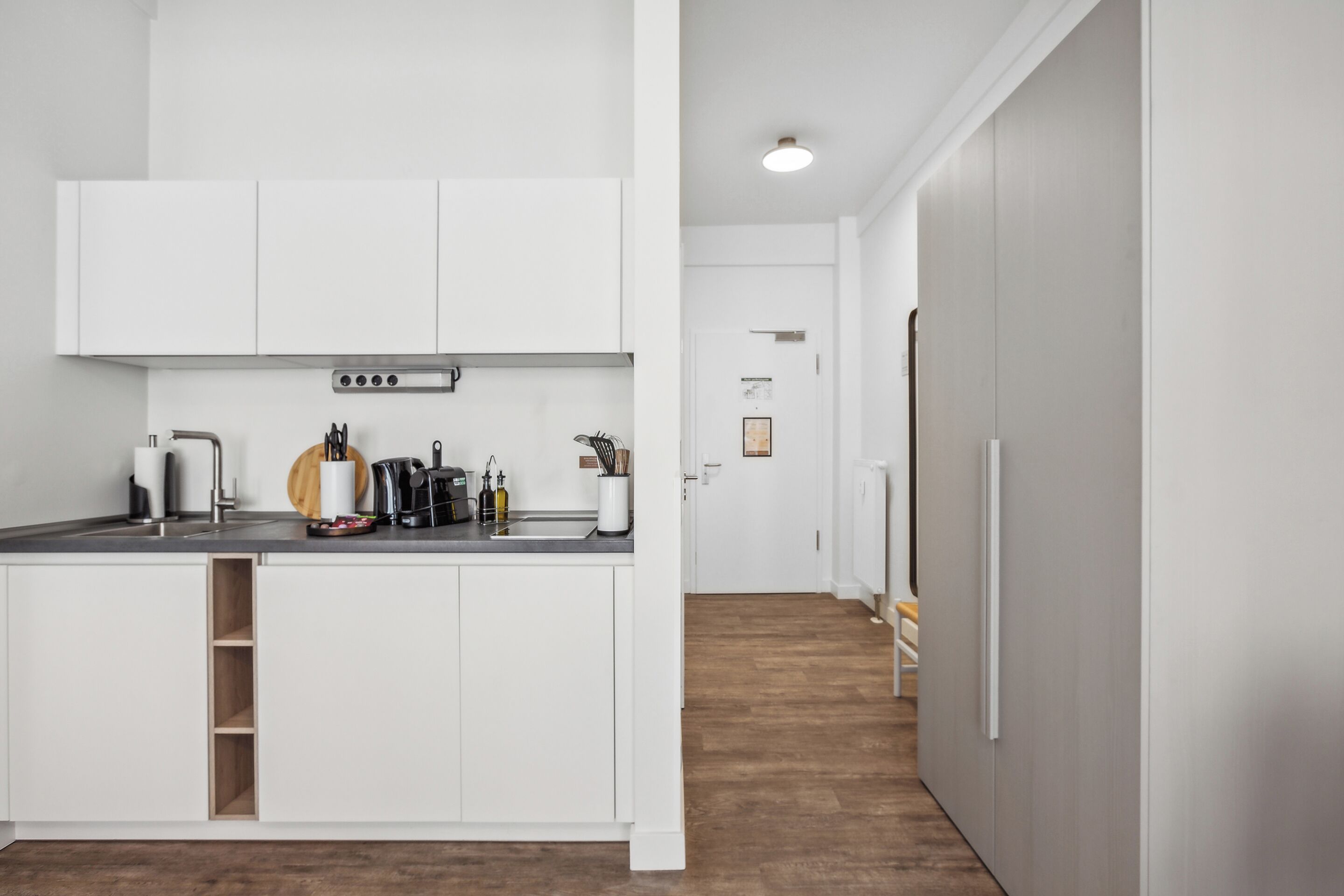 Una cocina moderna con armarios blancos, horno empotrado y campana extractora de acero inoxidable.