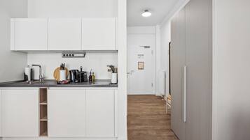 Una cocina moderna con armarios blancos, horno empotrado y campana extractora de acero inoxidable.