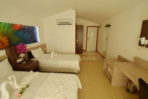 A hotel room with two beds, a wooden headboard, a painting, and a small table with a vase of flowers.