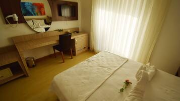 Una habitación de hotel con una cama, un escritorio, una silla, un espejo y un televisor.