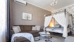 Ein gemütliches Schlafzimmer mit einer Couch, einem kleinen runden Tisch, einem Bett mit Baldachin und einer Wand-Klimaanlage.
