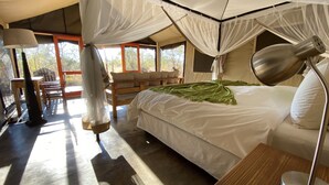 Un dormitorio con cama, lámpara de noche, silla y mesa.