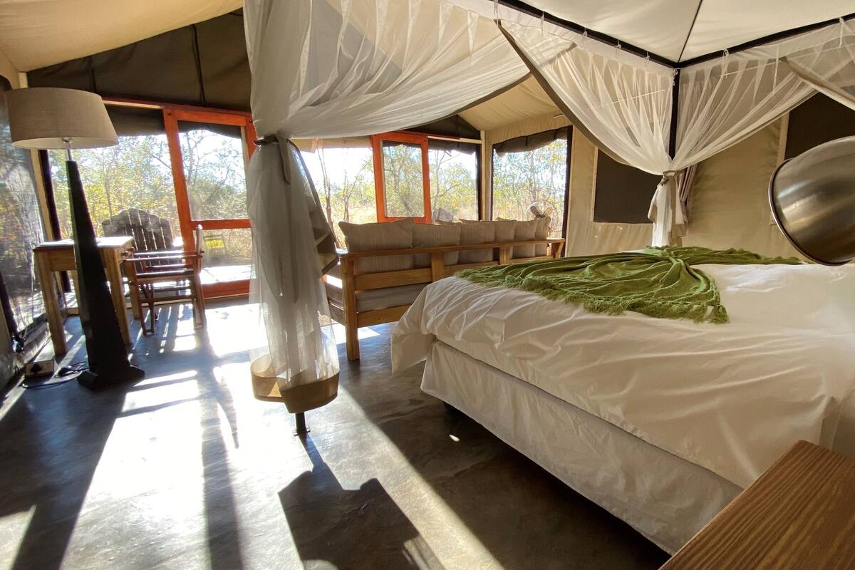 A bedroom with a bed, a bedside lamp, a chair, and a table.