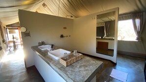 Un baño con dos lavamanos, un espejo grande y un techo con tela colgante.