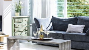 A modern living room with a grey sofa, a metal coffee table, and a green chest of drawers. - Tranquil Garden Retreat by Sea N Rent (Tel Aviv)