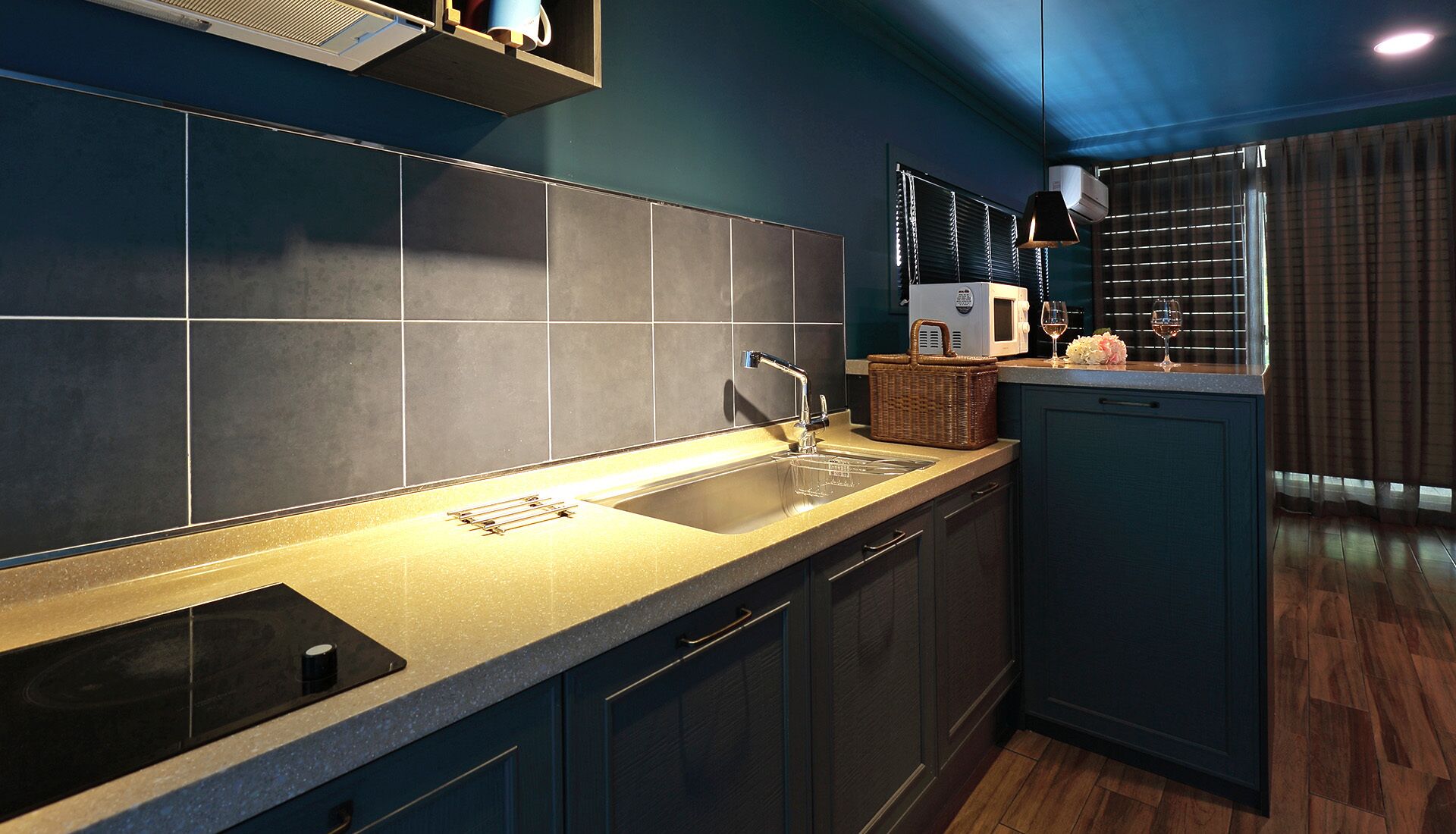 A modern kitchen with dark blue cabinets, a stainless steel sink, and a built-in microwave.