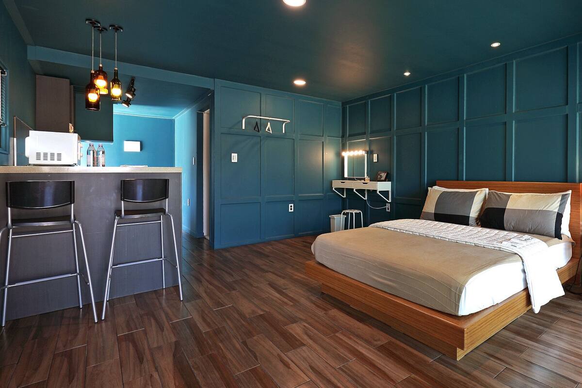 Een moderne slaapkamer met een houten bed, een klein bureau en een barretje.