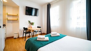 A hotel room with a bed, a desk, chairs, a TV, and a window with curtains. - Smartr Madrid Gran Vía 47 (Madrid)