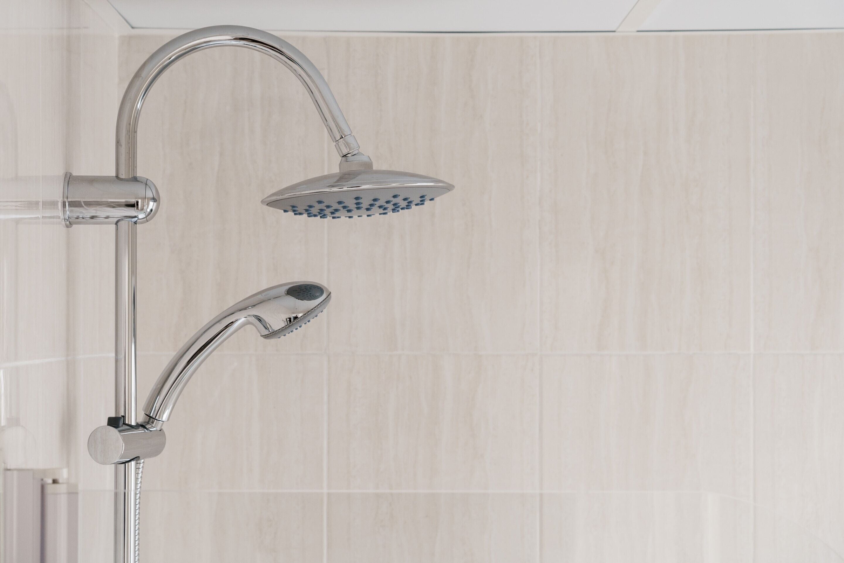 A modern shower with a handheld showerhead and a fixed overhead showerhead.