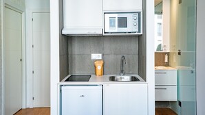A compact kitchen with a built-in microwave, a sink, and a dishwasher. - Smartr Madrid Gran Vía 47 (Madrid)