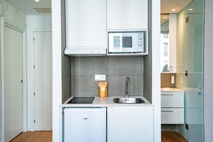 Una cucina compatta con forno a microonde integrato, lavandino e lavastoviglie.
