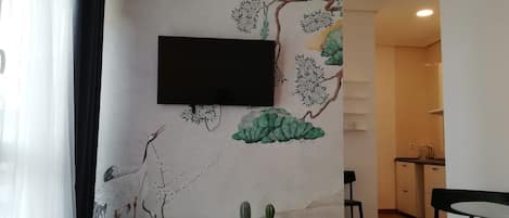 A modern living room with a flat-screen TV mounted on a wall with a nature-themed mural.